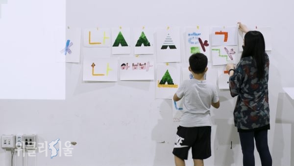 한 어린이가 가족과 함께 자신이 작업한 작품을 벽에 붙이고 있다.ⓒ위클리서울/ 서울문화재단